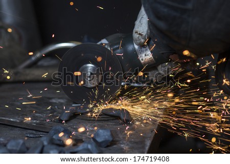 Electric wheel grinding on steel structure by worker in factory
