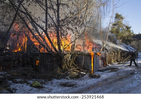 flames and smoke rise from burning wooden building