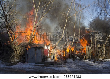 flames and smoke rise from burning wooden building