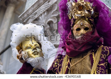 venetian figure in a fancy costume showing a carnival mask