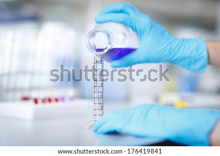 Decanting a violet liquid into a graduated cylinder in molecular laboratory