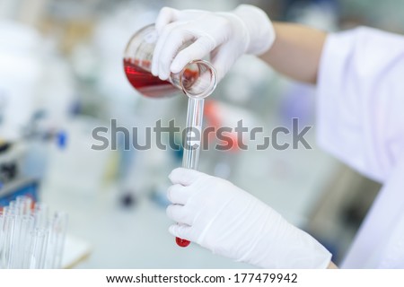 Decanting a violet liquid into a graduated cylinder in molecular laboratory