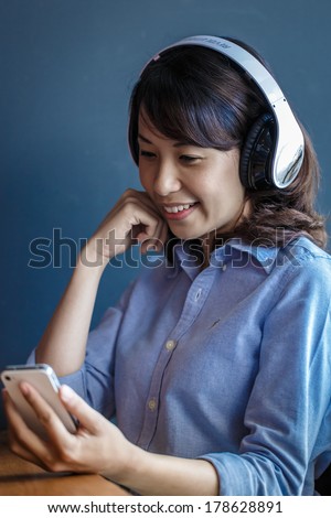 Young woman using smartphone at work with wireless headphone