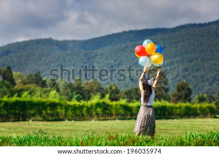 A girl playing balloon in grass field with mountain background