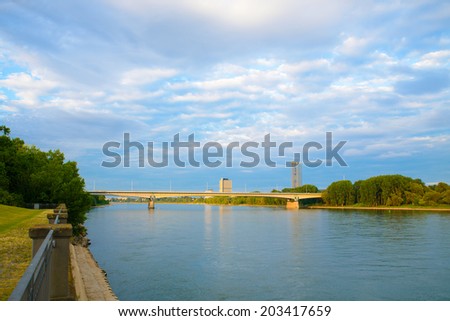 A landscape image of a river in the morning light with a cityscape in the distance