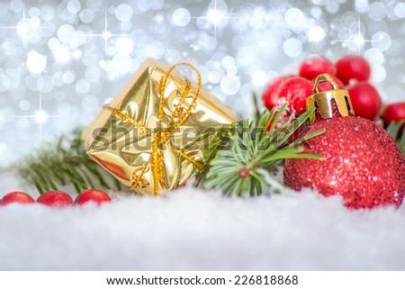 Yuletide image showing gifts, baubles, berries and fir branches against a shimmering celebration silver background