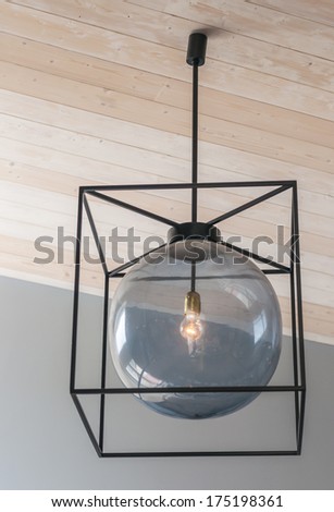 Modern metallic and glass chandelier hanging from ceiling on wooden background