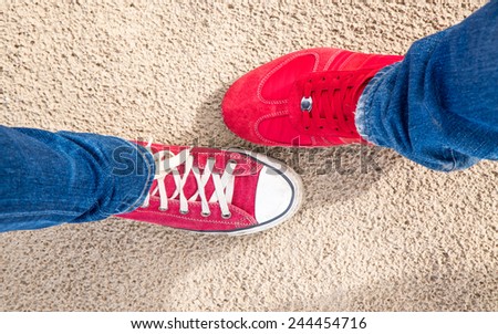 Two different pair of red shoes on the sand background