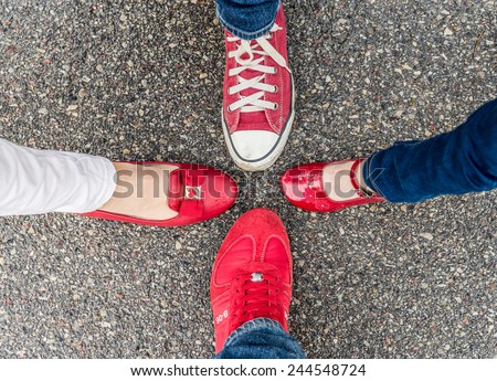Four different pair of red shoes on the sand asphalt