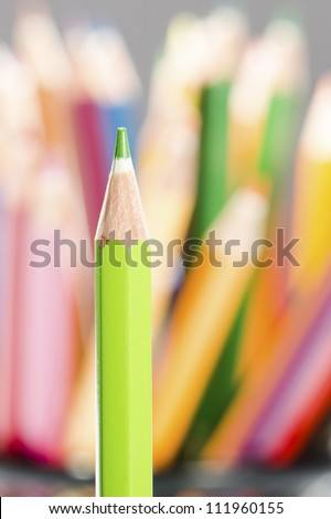 Single green pencil  against color pencils background macro