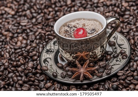 Cup of coffee with cherry, anise  and coffee beans