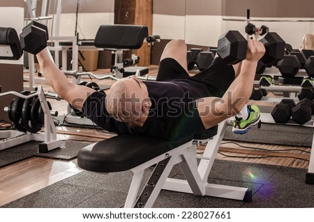 Man lifting weights sitting on his back in a gym