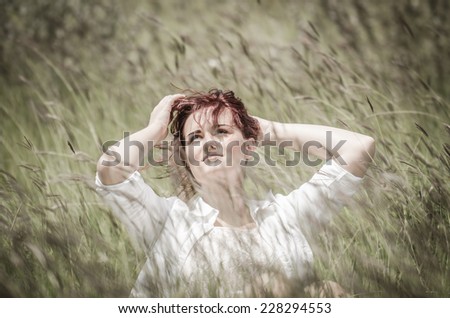 Young beautiful woman  sitting in wheat field under the summer sun