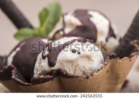 Vanilla ice cream cup with chocolate and nuts against rustic background