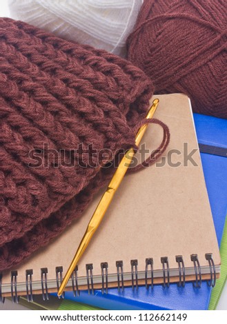 Brown crochet hat with golden hook, yarns and books isolated on white background. isolated on white background.