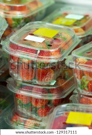 Fresh strawberries in closed plastic boxes in market.