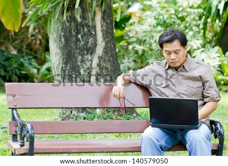 Asian man working with laptop in the park.