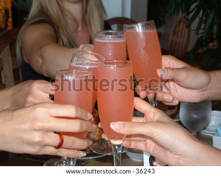 Women enjoying pink mimosa drinks at lunch.  women toasting with drinks in champagne glasses.