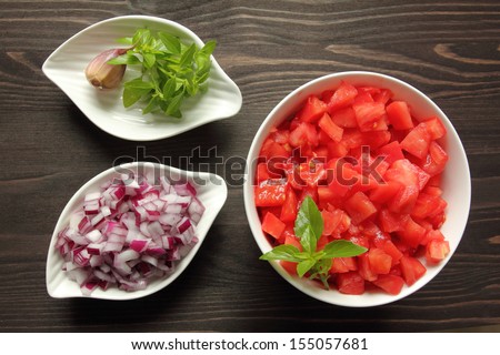 Bowls with chopped raw  tomatoes and onions on tomato sauce