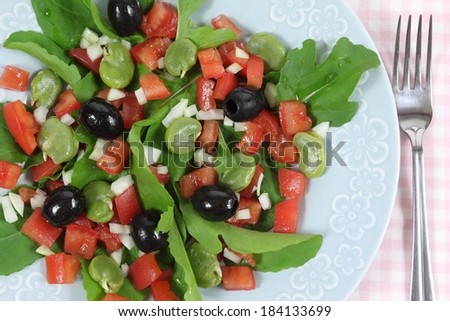 Fresh salad with tomatoes, broad beans, black olives and arugula