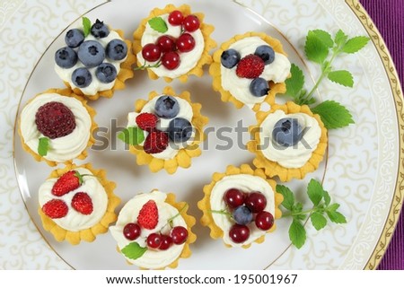 Fresh delicious fruit tarts with cream and berries on a plate