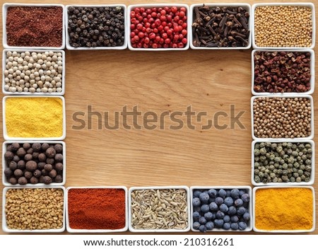 Herbs and spices in rectangular ceramic containers. Frame on a wooden background