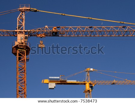 Industrial construction development. Yellow steel cranes against blue sky.