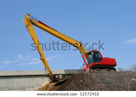 Construction industry machinery - red excavator working in road construction