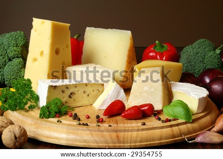 Variety of cheese and vegetables: camembert, gouda, brie with nuts, parmesan, goat, sheep and other hard cheeses