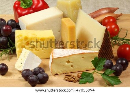Varieties of cheese on a wooden board. Grapes, tomatoes, rosemary and nuts.