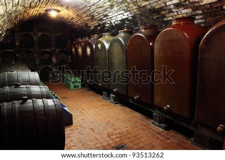 Old generic wine cellar - wooden barrels, huge ceramic containers and racks of bottles. Vintage wines.