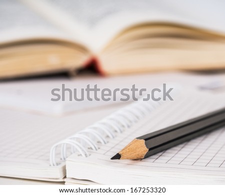 Wooden pencil, spiral squared paper notebook and opened book