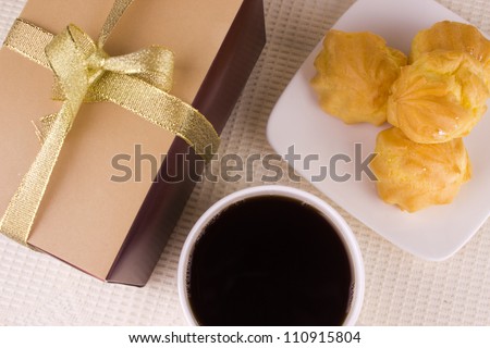 Cream cake with coffee and gift. Sweet Profiterole, Coffee and Present on the Table