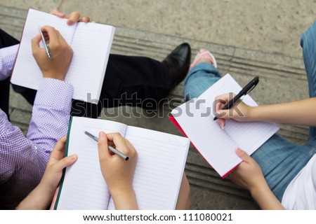 Teamwork of group people holding notebooks. Group of young students holding pen and writing in book