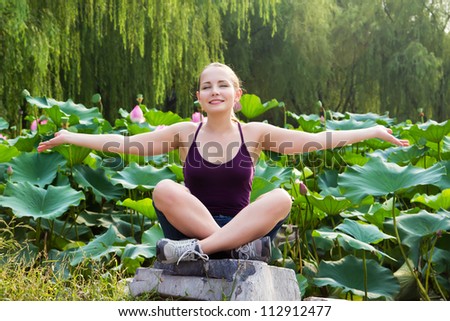 Beauty attractive woman sitting on stone and relaxing in lotus garden, she rising hands up to the sky