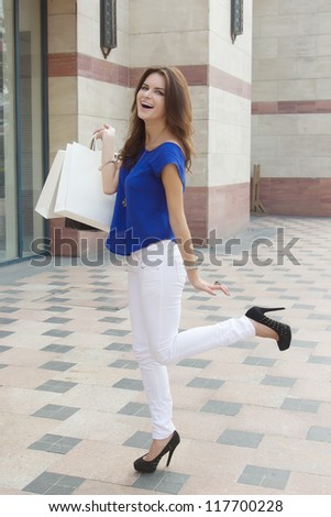 Smiling happy woman holding shopping bags and laughing. Caucasian young woman goes shopping