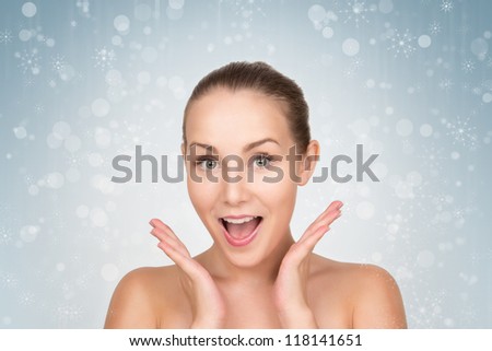 Christmas woman looking happy and exciting, female portrait over blue holiday background with shiny glowing glitters and bokeh lights. Beautiful  snow girl