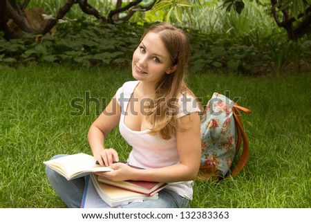 Young woman college student with book and bag studing in a park