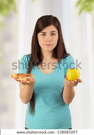 Young woman holding different food and selecting fat fastfood or low calorie fresh healthy fruit, diet concept