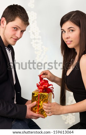 Couple opening yellow gift box with red ribbon together, love and romantic present