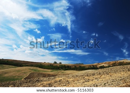 Deep blue and white sky over cultivated land in center italy