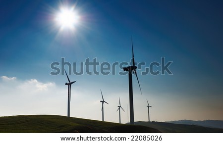 Four wind turbines silhouettes on top of hill
