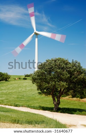 Solitary wind turbine and tree moving in the wind