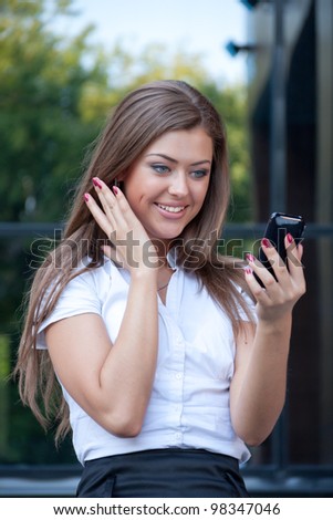 young woman looks in a cellular telephone and rejoices having seen something on the screen. Business style