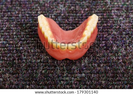 A set of dentures laying on a dark gray carpet