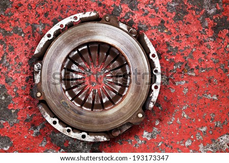 an old worn out vehicle clutch on a red background