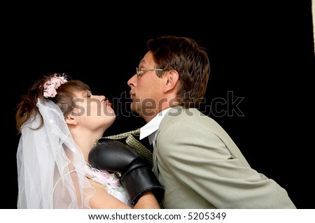 The bride kisses the groom on a black background