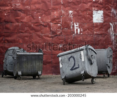 old riveted red metal wall with garbage containers