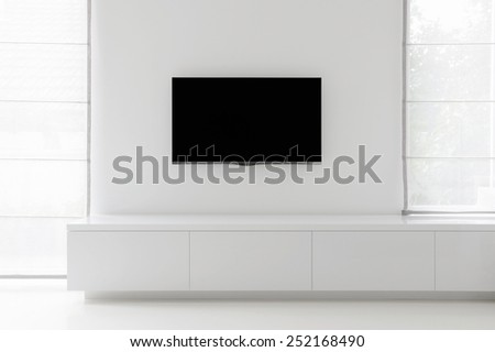 white living room detail tv on wall with commode and epoxy flooring