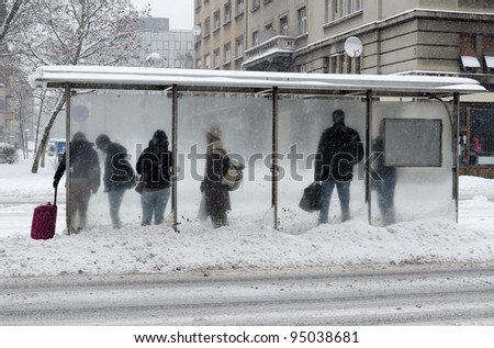 people waiting for street train while snowing